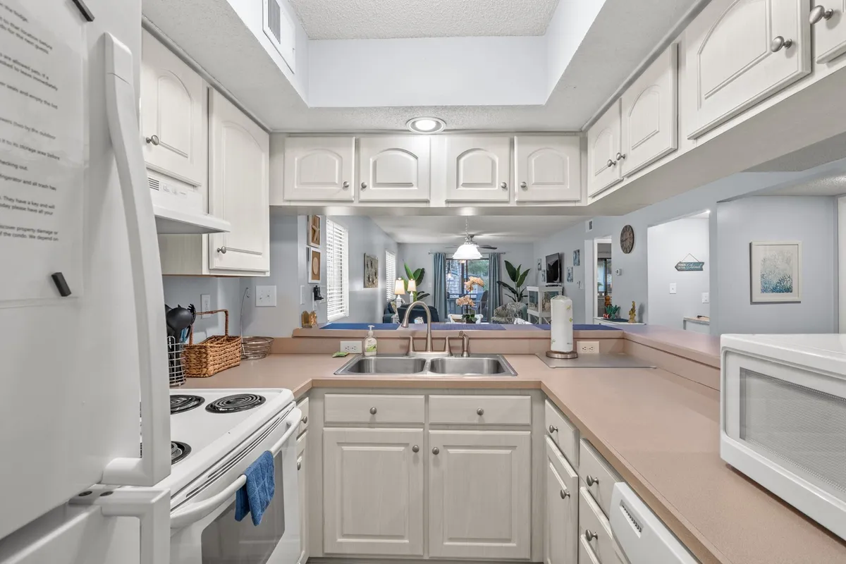 This image displays a welcoming kitchen with a spacious counter, a stainless steel sink, modern appliances, and decorative touches. The setup is ideal for cooking and entertaining, making it easy for families or friends to gather and prepare meals together.