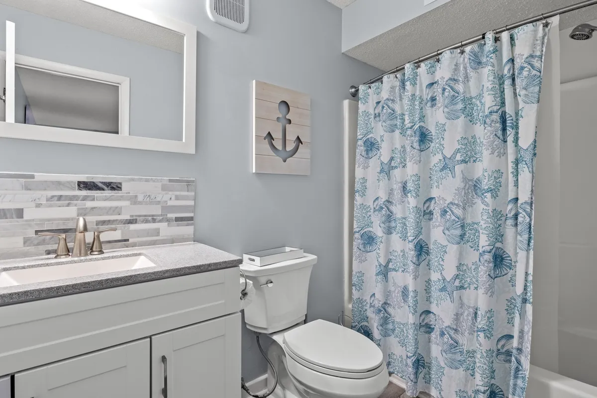 A modern, spa-inspired bathroom with a sleek sink, nautical-themed decor, and a shower curtain adorned with marine life designs. The overall ambiance is tranquil and relaxing, inviting guests to refresh after a long day.