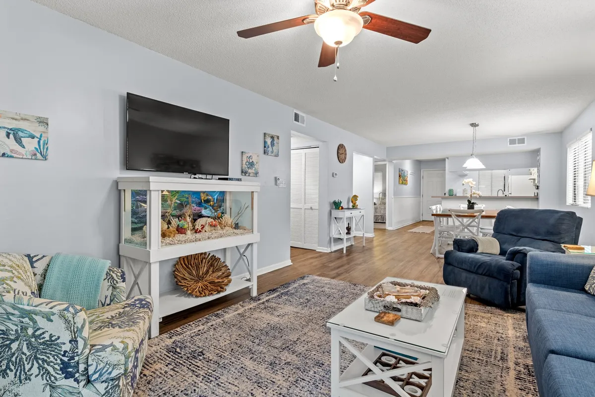 A comfortable living space featuring a sofa, coffee table, aquarium, and ceiling fan. The area exudes a welcoming vibe for entertainment, game nights, or quiet afternoons, and is well-suited for families to gather and unwind.